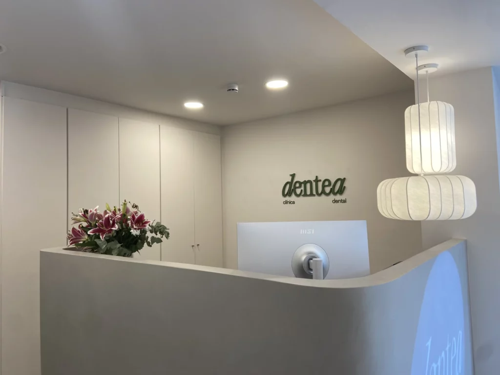 Recepción de Dentea con flores, iluminación cálida y el logo en la pared